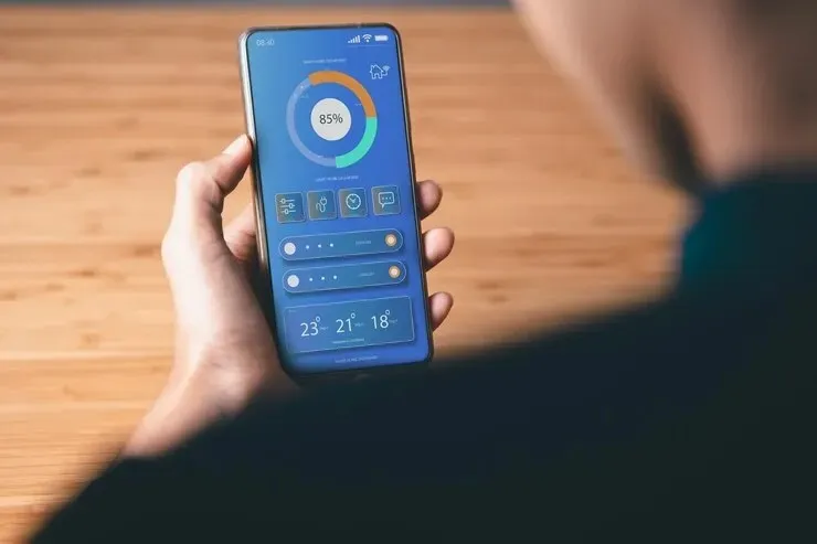 رجل يمسك هاتفه الذكي ويتفاعل مع واجهة تطبيق تسريع الهاتف وتنظيف الملفات المخفية، يعكس محاولة تحسين الأداء وتحرير مساحة التخزين والتعامل مع مشاكل البطء والذاكرة في الهواتف الذكية في 2026