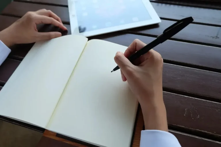 يد تمسك قلمًا أسود فوق خلفية بيضاء، بما يناسب موضوع كتابة مقدمة مقال جذابة تشد انتباه القارئ من البداية.